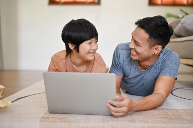 Felice papà asiatico sta guardando un film sul suo laptop e si sta divertendo in famiglia con suo figlio