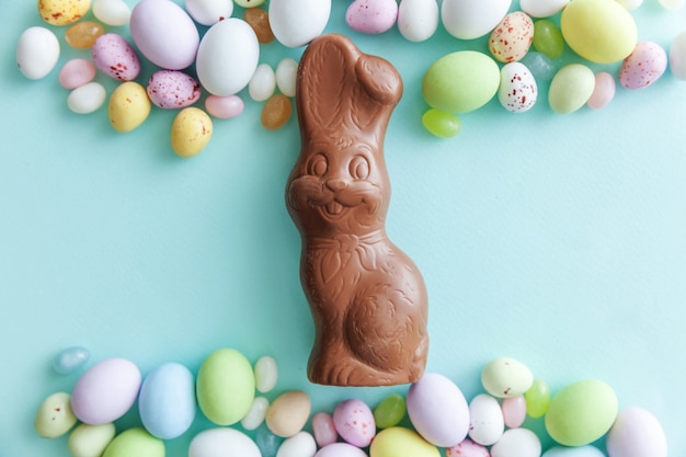 Felice Pasqua concetto. Preparazione per le vacanze. Coniglietto di uova di cioccolato caramelle di Pasqua e dolci di gelatina isolati su priorità bassa blu pastello alla moda