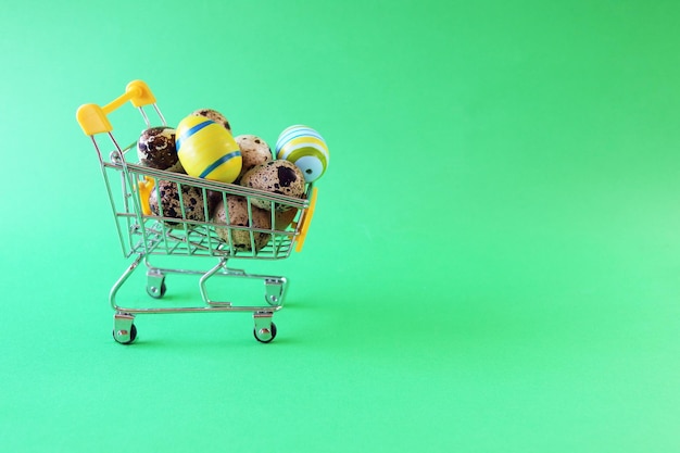 Felice Pasqua supermercato carrello giocattolo riempito con quaglie e uova colorate sfondo verde brillante