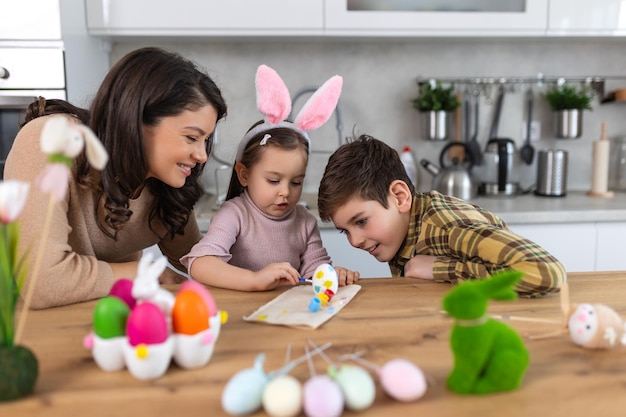 Felice Pasqua Una madre, un figlio e sua figlia dipingono uova di Pasqua Una famiglia felice che si prepara per la Pasqua Una bambina carina che indossa orecchie di coniglio il giorno di Pasqua