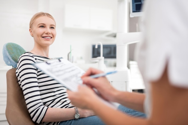 Felice paziente seduto davanti al suo dentista sorridente essendo grato dopo il suo trattamento dentale