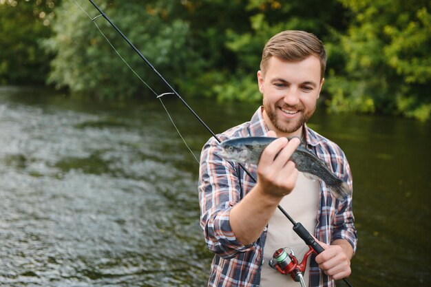 Felice pescatore in possesso di un pesce catturato Pesca sul bellissimo fiume