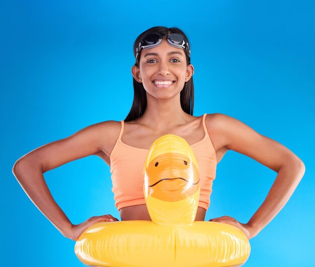 Felice piscina galleggiante e ritratto di donna in studio per il nuoto estivo e le vacanze Sorriso felicità e vacanza al mare con femmina e anatra gonfiabile su sfondo blu sicurezza giocosa e divertente