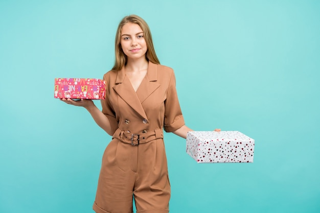 Felice piuttosto giovane donna azienda confezione regalo su sfondo blu.