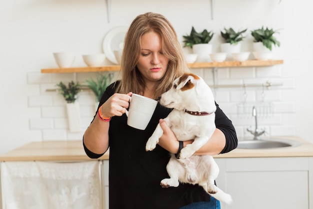 Felice proprietaria del cane jack russell terrier, sente la responsabilità di prendersi cura dell'animale domestico, in piedi sullo sfondo della cucina. Persone e rapporto con gli animali