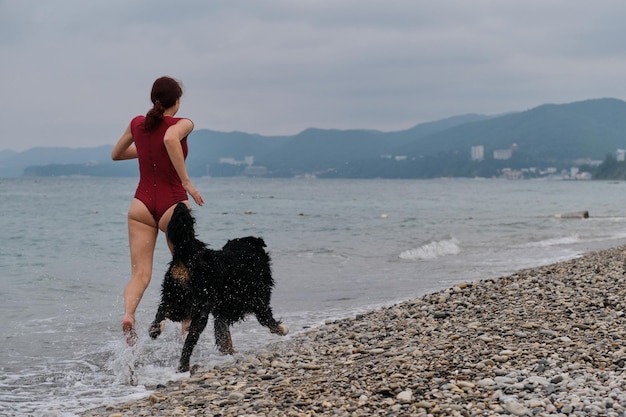 Felice proprietario di Bovaro del Bernese in vacanza sulla spiaggia Donna dai capelli rossi carina caucasica