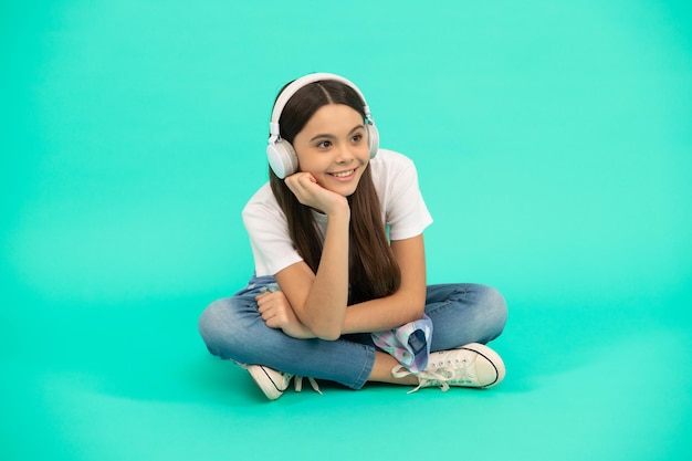 Felice ragazza adolescente in cuffia ascolta musica wireless auricolare dispositivo accessorio nuova tecnologia sviluppo dell'infanzia bambino in auricolari moderni educazione online torna a scuola