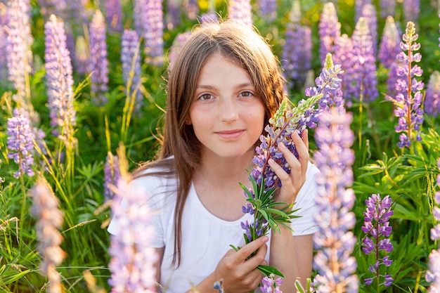 Felice ragazza adolescente sorridente all'aperto. Bella giovane donna teenager che riposa sul campo estivo con sfondo verde fiori selvatici in fiore