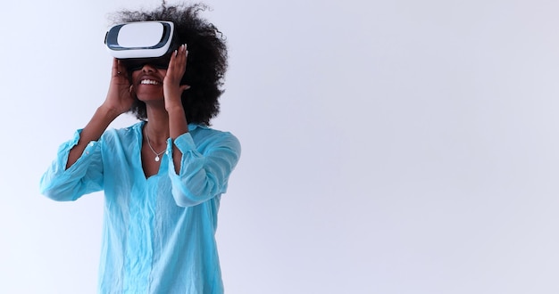 Felice ragazza afroamericana che ottiene esperienza utilizzando gli occhiali per cuffie VR della realtà virtuale, isolati su sfondo bianco