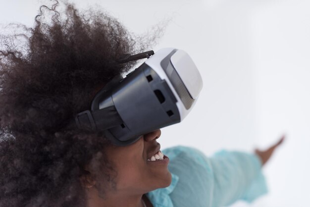 Felice ragazza afroamericana che ottiene esperienza utilizzando gli occhiali per cuffie VR della realtà virtuale, isolati su sfondo bianco