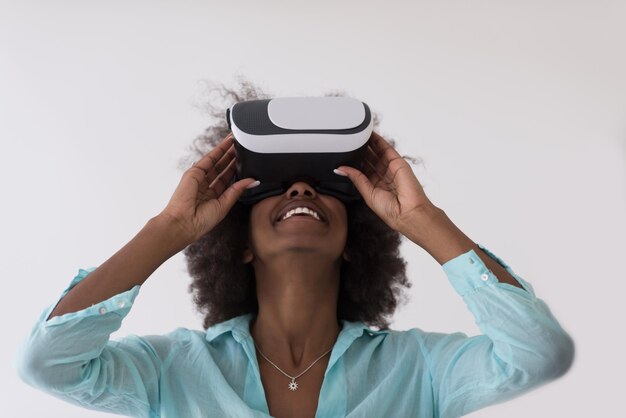 Felice ragazza afroamericana che ottiene esperienza utilizzando gli occhiali per cuffie VR della realtà virtuale, isolati su sfondo bianco