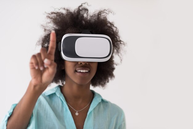 Felice ragazza afroamericana che ottiene esperienza utilizzando gli occhiali per cuffie VR della realtà virtuale, isolati su sfondo bianco