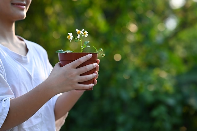 Felice ragazza asiatica che tiene in mano un vaso di fiori Salvando il concetto di giornata mondiale della terra