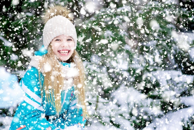 Felice ragazza bionda bambino nella foresta innevata