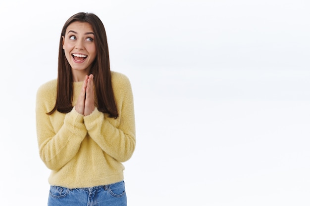 Felice ragazza eccitata che applaude o si sfrega le mani dal gusto e dalla felicità, sorridendo guardando la competizione vincente, ricevendo ricompensa e festeggiando, muro bianco