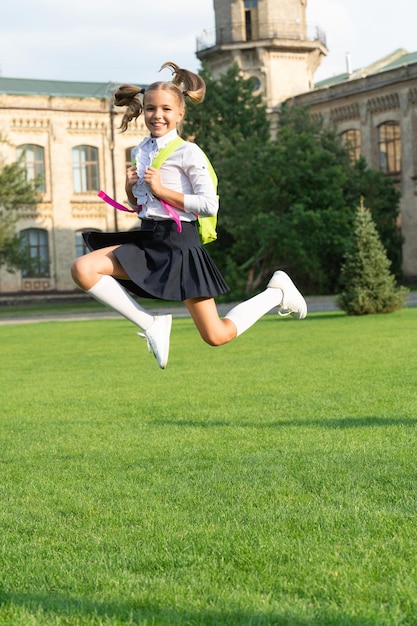 Felice ragazza energica in uniforme torna a scuola saltando di gioia 1 settembre