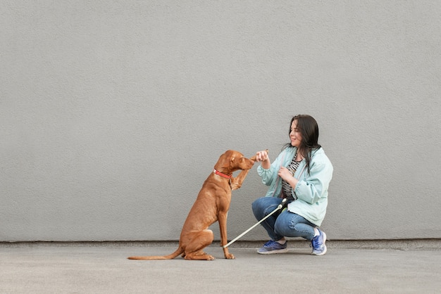 Felice ragazza in abbigliamento casual addestra un cane