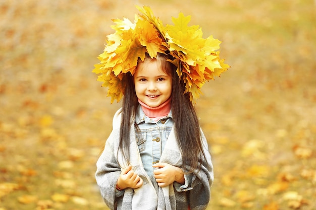 Felice ragazza in giallo ghirlanda di autunno nel parco