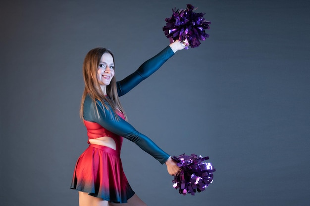 Felice ragazza pon pon in uniforme che balla con pompon isolati su sfondo grigio