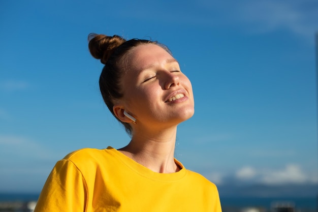 Felice ragazza positiva giovane bella donna sta ascoltando musica canzone in auricolari wireless meditare