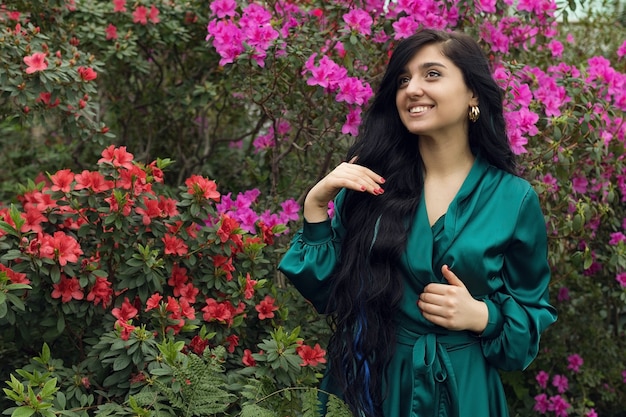 Felice ragazza sorridente nel giardino fiorito, bellissimo giardino di fiori rosa. Foto di alta qualità