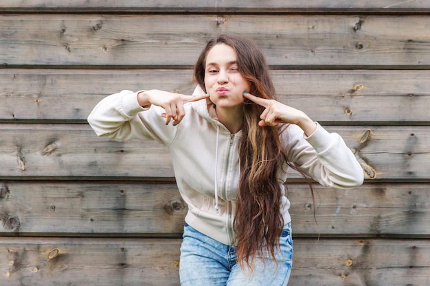 Felice ragazza sorridente. Ritratto di bellezza giovane donna bruna che ride in posa con l'espressione del viso di bacio sul fondo della parete di legno. donna europea. Emozione umana positiva