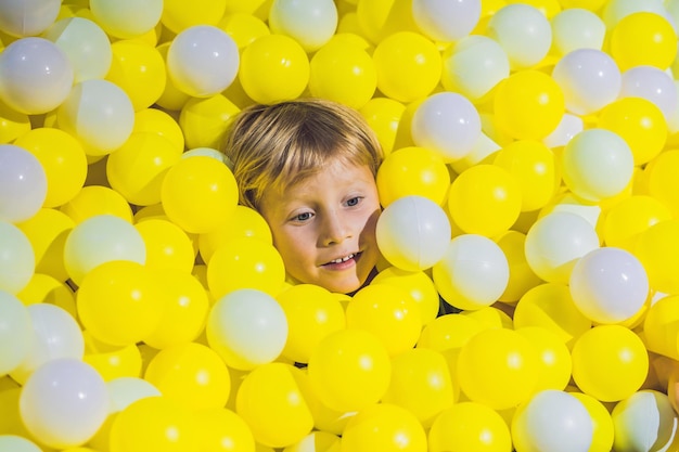 Felice ragazzino che gioca al campo da giuoco con palline di plastica colorate ad alta vista. Adorabile bambino che si diverte al chiuso.