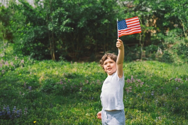 Felice ragazzino patriottico che tiene la bandiera americana USA celebra il 4 luglio Felice giorno dell'indipendenza