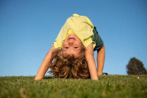 Felice ragazzino sdraiato a testa in giù sull'erba bambini che esplorano la natura estate