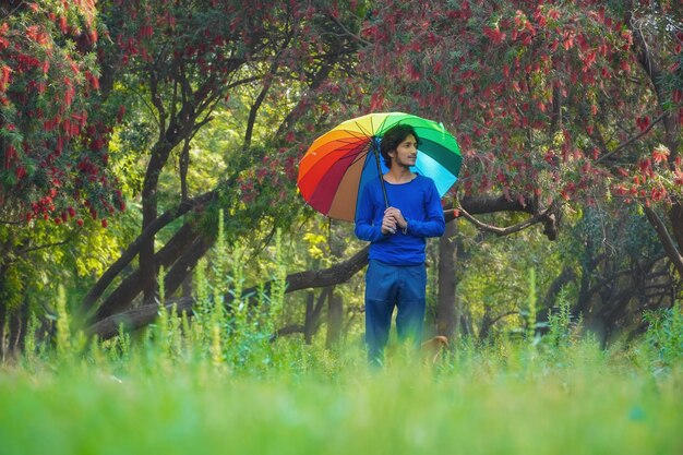 Felice ragazzo asiatico che tiene ombrello colorato in estate all'aperto