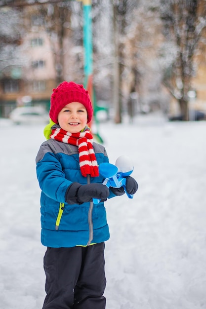 Felice ragazzo che gioca con la neve in una passeggiata invernale nevosa facendo palle di neve nel parco