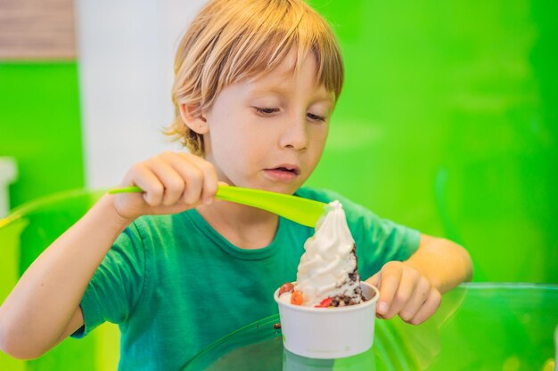 Felice ragazzo che mangia un gustoso gelato o yogurt gelato