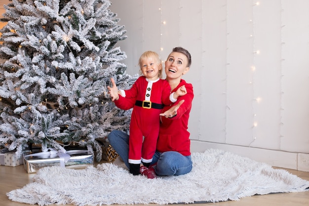 Felice ragazzo e madre vicino all'albero di Natale. Natale, vacanze e concetto di infanzia