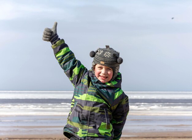 Felice ragazzo energico attivo passeggiate vicino alla baia gioca dà un pollice in alto sorrisi