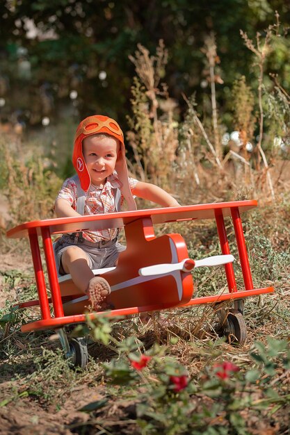 Felice ragazzo ragazzo pilota seduto e giocando con l'aeroplano giocattolo rosso in estate Sogna il bambino del viaggio