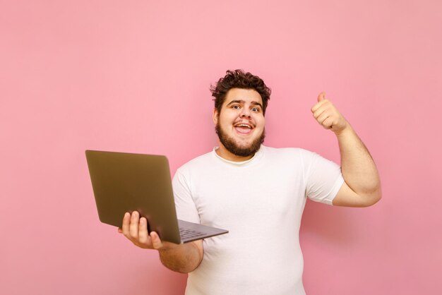 Felice ragazzo sovrappeso è felice di vincere con un laptop in mano