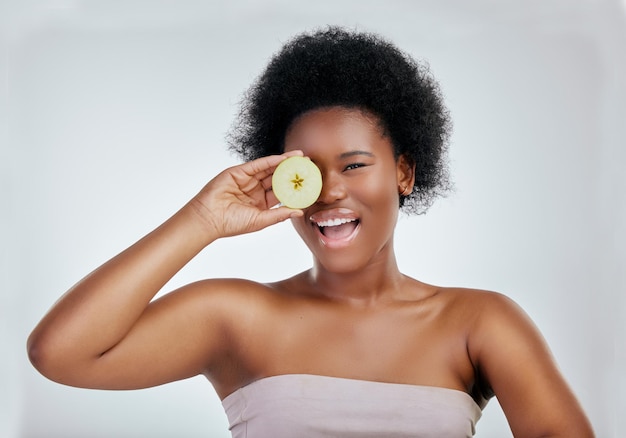 Felice ritratto di donna nera e mela per la dieta naturale nutrizione o salute su uno sfondo bianco studio Volto di donna africana sorriso con frutta biologica per fibre vitamine o cura del corpo