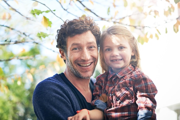 Felice ritratto e padre con la figlia nel giardino sul retro per abbracciare il legame o la felicità affettuosa rilassarsi ed eccitarsi con l'uomo e la ragazza all'aperto per abbracciare l'autunno e la cura