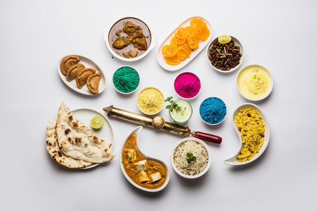 Felice Santo concetto mostra indiano pranzo assortito cibo come burro paneer masala naan jeera riso nero chana fry jalebi ras malai thandai e Farsan con colori holi e pichkari