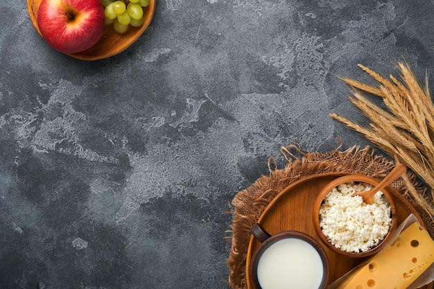 Felice Shavuot Sfondo per Shavuot tradizionale celebrazione religiosa ebraica Latte e formaggio grano maturo e frutta Prodotti lattiero-caseari su vecchio sfondo grigio scuro Concetto Shavuot Vista dall'alto Mock up