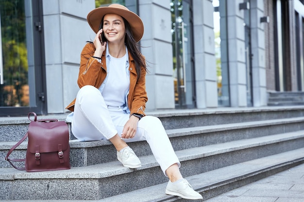 Felice signora attraente in cappello utilizzando smartphone