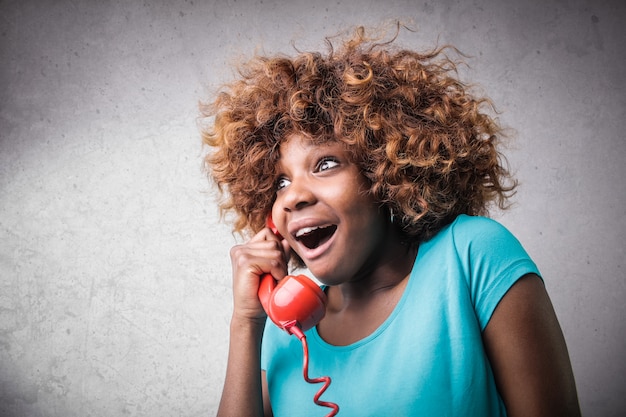 Felice sorpresa ragazza afro al telefono