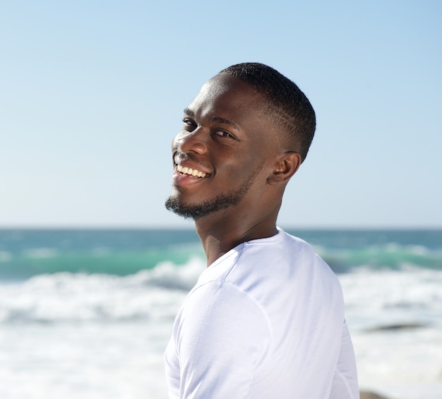 Felice sorridente allegro giovane in spiaggia