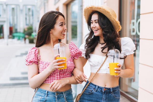 Felice sorridente bella bruna giovani donne amici in abiti estivi con succo nelle mani