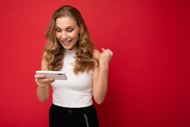 felice sorridente concentrato bella giovane donna bionda che indossa la maglietta bianca isolata