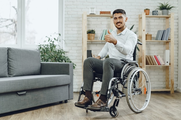 Felice sorridente giovane uomo su una sedia a rotelle stare a casa