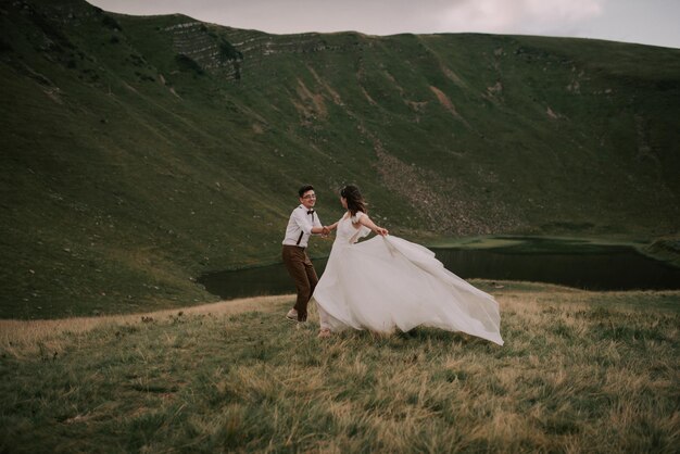 Felice splendida sposa e sposo che camminano tenendosi per mano in stile boho sposi splendida coppia in montagna con uno straordinario scenario spazio per il testo