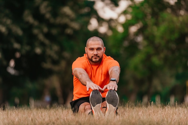 Felice sportivo positivo durante l'allenamento all'aperto uomo che indossa abbigliamento sportivo che riscalda i muscoli godendosi uno stile di vita attivo fuori nel parco