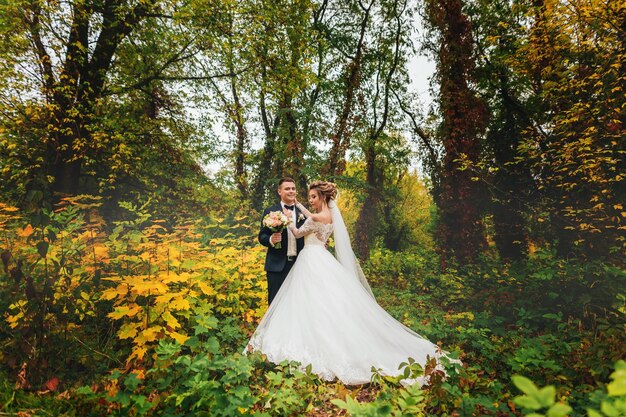 felice sposa e sposo che camminano nella foresta di autunno