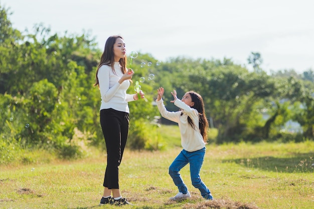 Felice stile di vita asiatico famiglia madre, padre e bambina carina divertirsi insieme e godersi il gioco all'aperto soffiando bolle di sapone nel parco giardino in una giornata di sole, estate